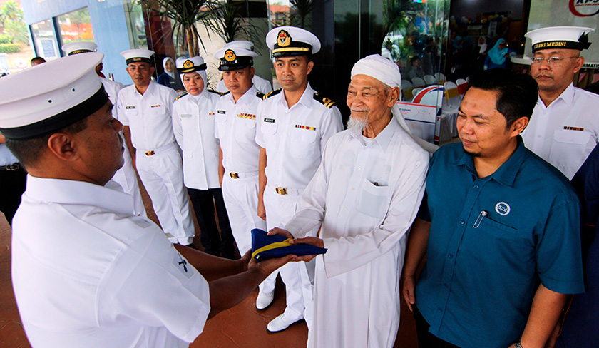 Mohamed Sharif menyerahkan Jalur Gemilang kepada Laskar Kanan Peperangan Atas Permukaan Airulham Ali (depan) dari unit Pasukan Simpanan Sukarela TLDM KD Sri Medini Kem Tebrau sebagai gimik pelancaran Sambutan Kemerdekaan ke-62 di Hospital Pakar KPJ Pasir Gudang, 25 Ogos, 2019. --fotoBERNAMA