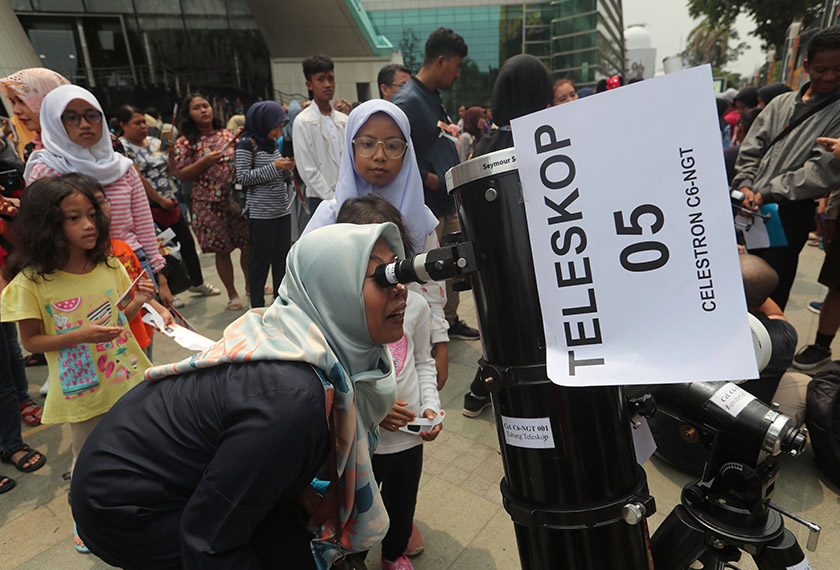 Orang ramai turut menggunakan kaca mata istimewa sambil mendongak melihat fenomena tersebut selama lebih dua minit. Foto: AP
