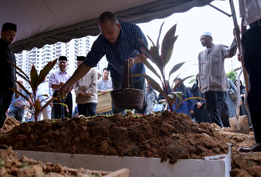 Rosli menabur bunga di atas pusara ayahnya. - BERNAMA