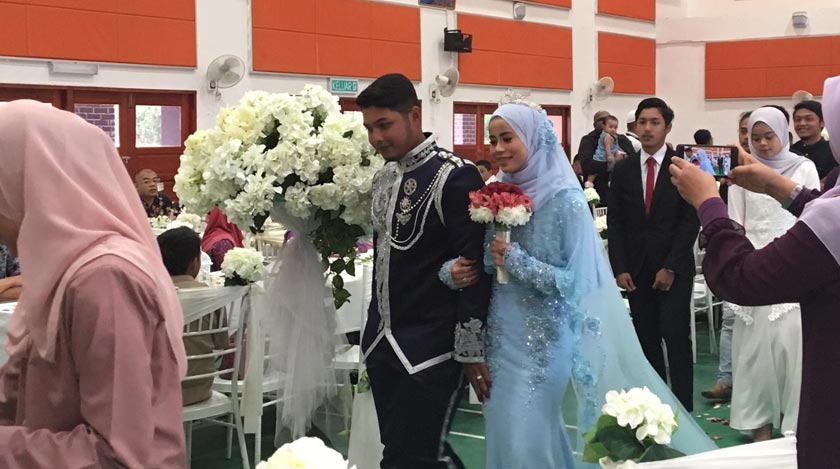 Pasangan pengantin diiring ke pelamin.