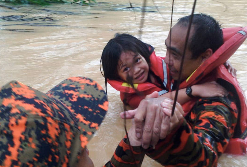 Dua anggota bomba memindahkan seorang kanak-kanak ke tempat selamat di Taritipan, Kota Marudu, Sabah Sabtu lalu. - BERNAMA