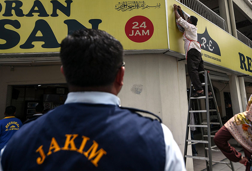 Pekerja premis makanan di Jalan Metro Perdana Timur 3, Kepong menutup tanda halal di papan tanda perniagaan restoran tersebut selepas mendapat arahan daripada KPDNHEP dan Jakim selepas mendapati logo halal yang dipamerkan tidak menepati piawaian yang ditetapkan. - BERNAMA