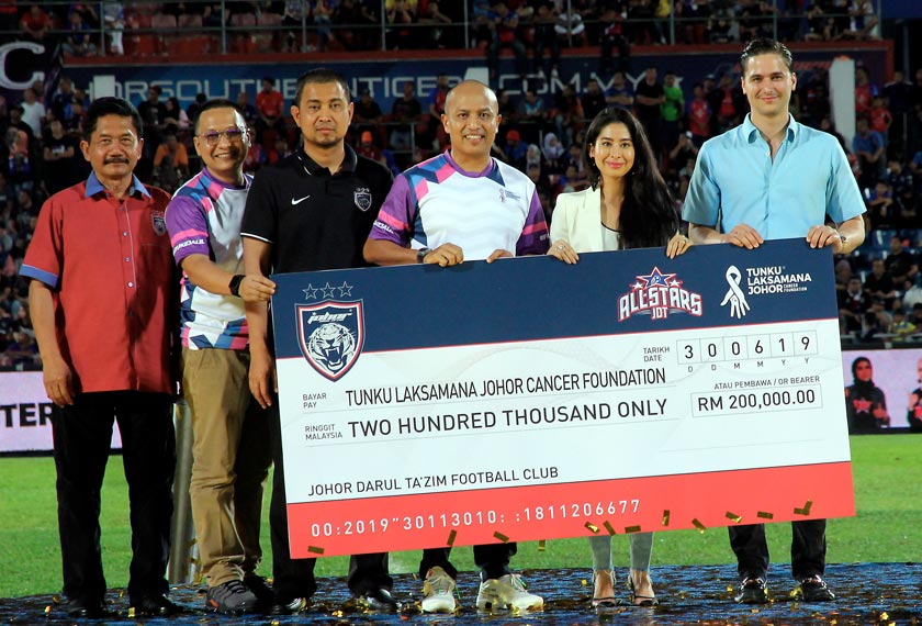 Tunku Puteri Johor Tunku Tun Aminah Sultan Ibrahim (dua, kanan) yang juga Presiden Kelab Bola Sepak Johor Darul Ta'zim (JDT) berkenan menyerahkan replika cek hasil kutipan Perlawanan Amal JDT All Stars kepada wakil Persatuan Kanser Tunku Laksamana Johor selepas selesai perlawanan di Stadium Tan Sri Dato' Haji Hassan Yunos malam tadi. - BERNAMA