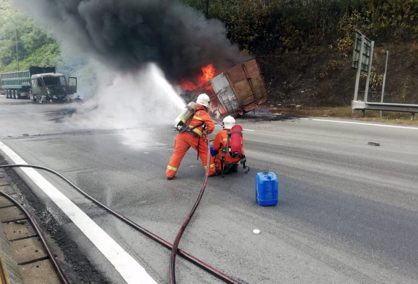 Anggota Bomba cuba memadamkan api menggunakan buih.