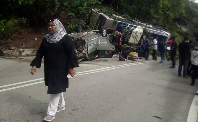 Seorang wanita melintasi lokasi kejadian sebuah bas yang terlibat dalam kemalangan di laluan dekat Bukit Tangga, Negeri Sembilan. - Foto: Media sosial