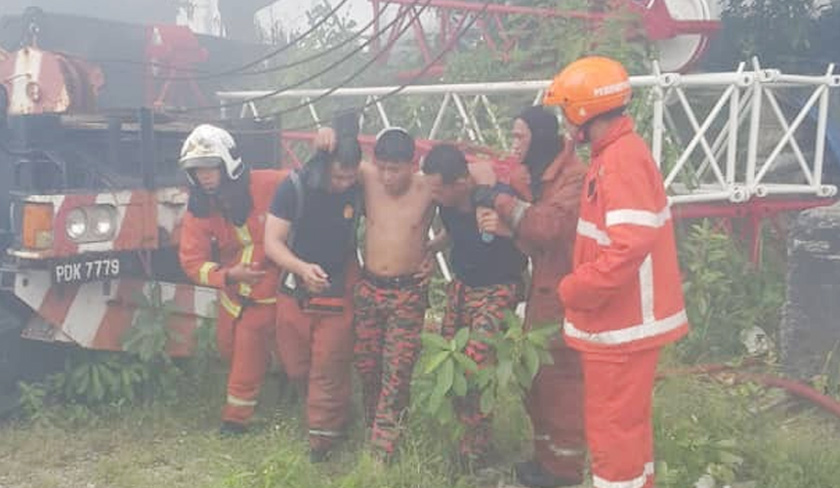 Salah seorang anggota bomba yang sedang memadam kebakaran terpaksa dipapah kerana mengalami sesak nafas. - Foto JBPM