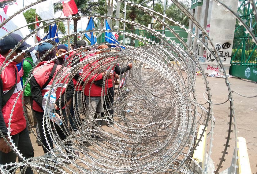 Penunjuk perasaan menggunakan kain dan kadbod untuk melepasi halangan keluli yang diletakkan di hadapan bangunan DPR. Pasukan Ceritalah