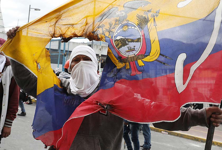 Seorang penunjuk perasaan memegang bendera negara yang telah koyak ketika mengadakan demonstrasi menentang Presiden Lenin Moreno dan dasar-dasar ekonominya di Quito, Ecuador, 8 Okt, 2019. (Foto AP)