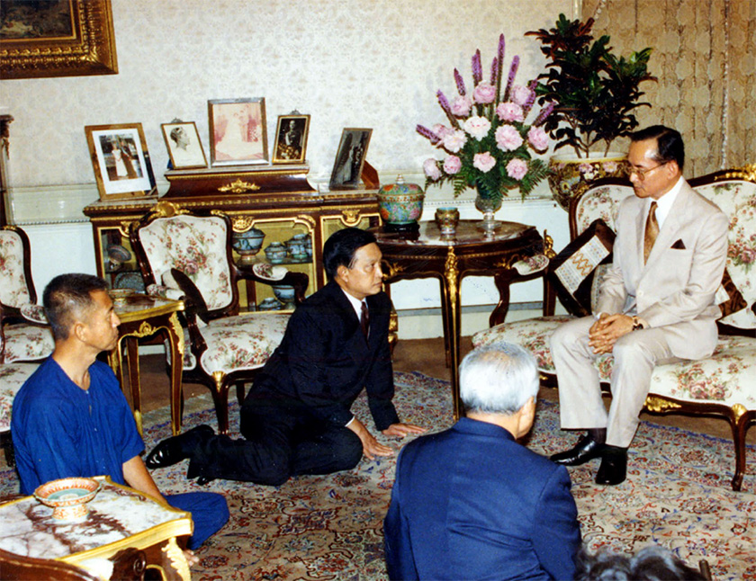Raja Bhumibol (Rama IX) Thailand duduk di kerusi sambil sekumpulan ahli politik di hadapannya mengadapnya sambil duduk di atas lantai, 20 Mei, 1992. Biro Istana/Ceritalah
