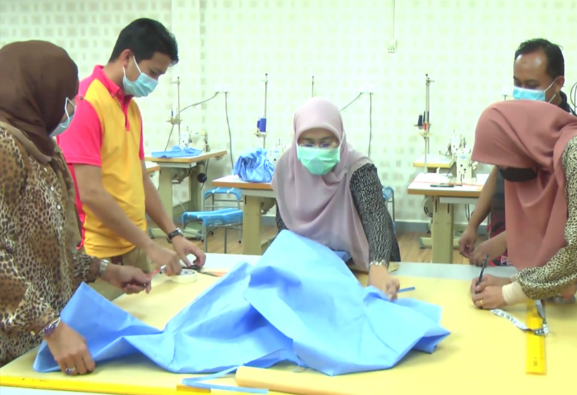 Pelajar UUM mengukur kain tanpa tenun khas untuk dijadikan gaun PPE. 