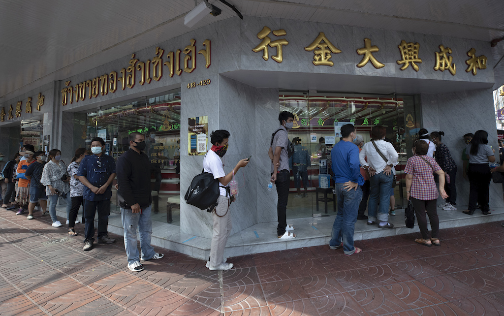 Customers practicing social distancing to help curb the spread of the coronavirus wait to enter a gold shop for sold in Bangkok, Thailand, Thursday, April 16, 2020. With gold prices rising to a seven-year high, many Thais have been flocking to gold shops to trade in their necklaces, bracelets, rings and gold bars for cash, eager to earn profits during an economic downturn. (AP Photo/Sakchai Lalit)