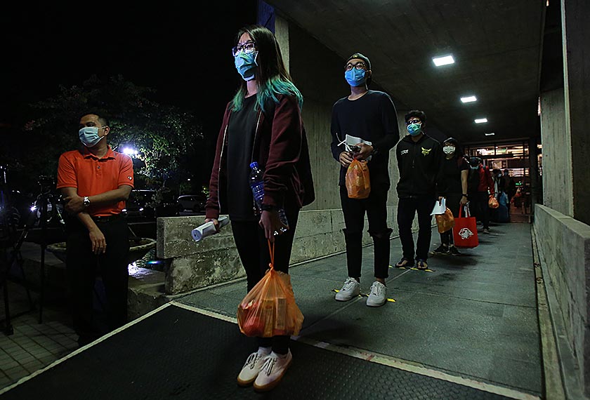 Penuntut UM dilihat memakai topeng muka dan mengamalkan penjarakan sosial sewaktu beratur untuk menaiki bas yang disediakan. - gambar Universiti Malaya