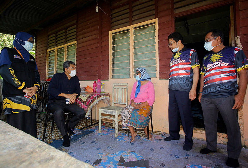 Zahidi (dua, kanan) dan ADUN Rantau Datuk Seri Mohamad Hasan (dua, kiri) beramah mesra dengan salah seorang penduduk ketika mengadakan ziarah kasih pada Program Konvoi Kembara Ziarah Kasih Merdeka di Dewan Eco Park Kuala Sawah, Rantau, hari ini. - Bernama