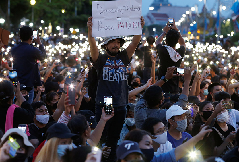 Pro-democracy protesters use mobile phones as flashlights at a rally as one of them is holding a placard at a rally to demand the government to resign, to dissolve the parliament. REUTERSpic
