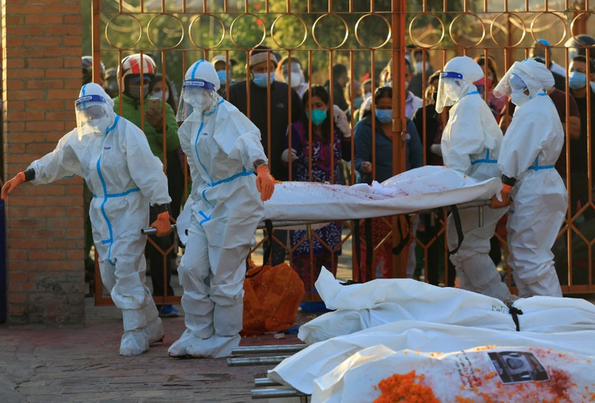 Female soldiers wearing personal protective equipment (PPE) lift a stretcher with the body of a coronavirus victim as family members mourn at a crematorium. REUTERSpic
