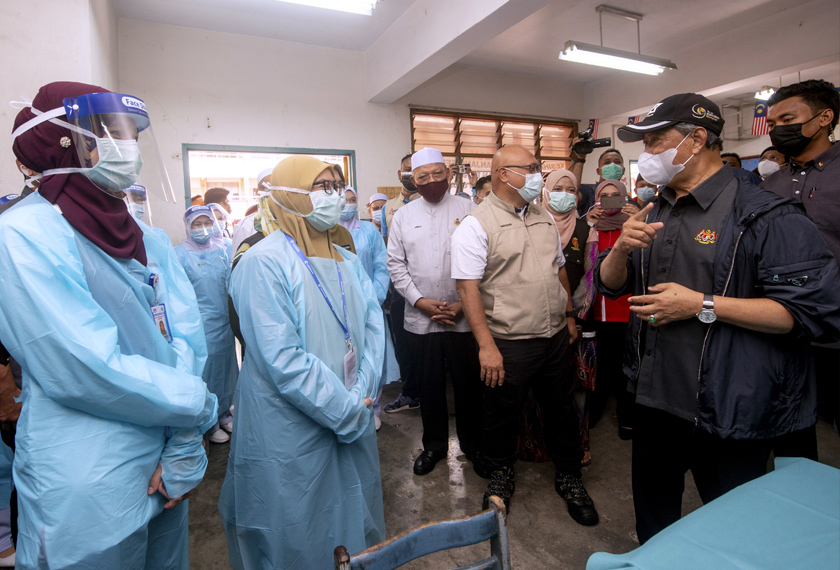 Muhyiddin (dua, kanan) menanyakan sesuatu kepada para petugas KKM Pasir Mas Klinik sementara di Pusat Pemindahan Sementara (PPS) Sekolah Kebangsaan Gual Tinggi sempena lawatan kerja beliau hari ini. - Foto Bernama