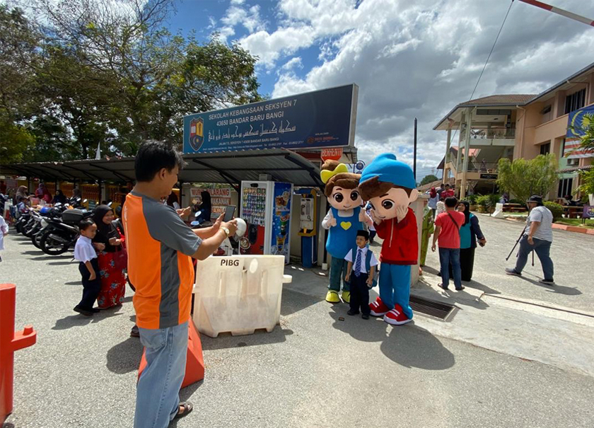 Seorang bapa yang tidak menang tangan mengambil gambar anaknya bersama maskot Omar & Hana. - Astro AWANI/ ISABELLE LEONG