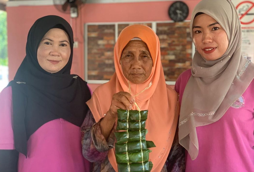 Junaidah (kiri) bersama Hajjah Dayang Suma (tengah) antara individu yang mahir menghasilkan kuih kelupis. - Foto Astro AWANI/Hasimi Muhamad