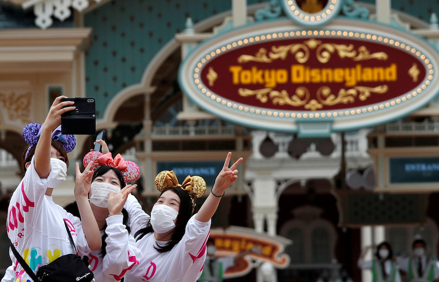 Visitors take a photo after the reopening of Tokyo Disneyland along with Tokyo DisneySea, which closed for months due to the coronavirus disease (COVID-19) outbreak, at the entrance gate of Tokyo Disneyland in Urayasu, east of Tokyo, Japan July 1, 2020. REUTERS/Issei Kato