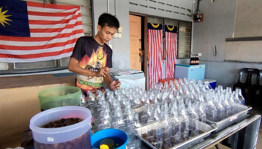 Salah seorang pekerja di kedai Mohd Fadzil sedang mengisi jus jambu ke dalam botol. - Foto Astro AWANI