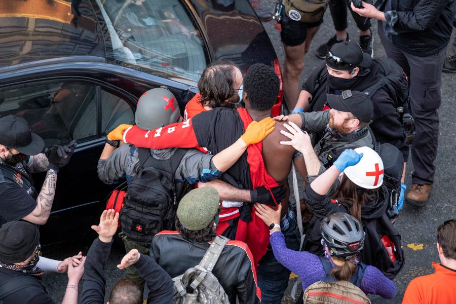 An injured man is taken away from the scene after a gunman drove toward protesters Sunday, June 7, 2020, in Seattle. Authorities say the driver hit a barricade then exited the vehicle brandishing a pistol. At least one person was injured. (Dean Rutz/The Seattle Times via AP)