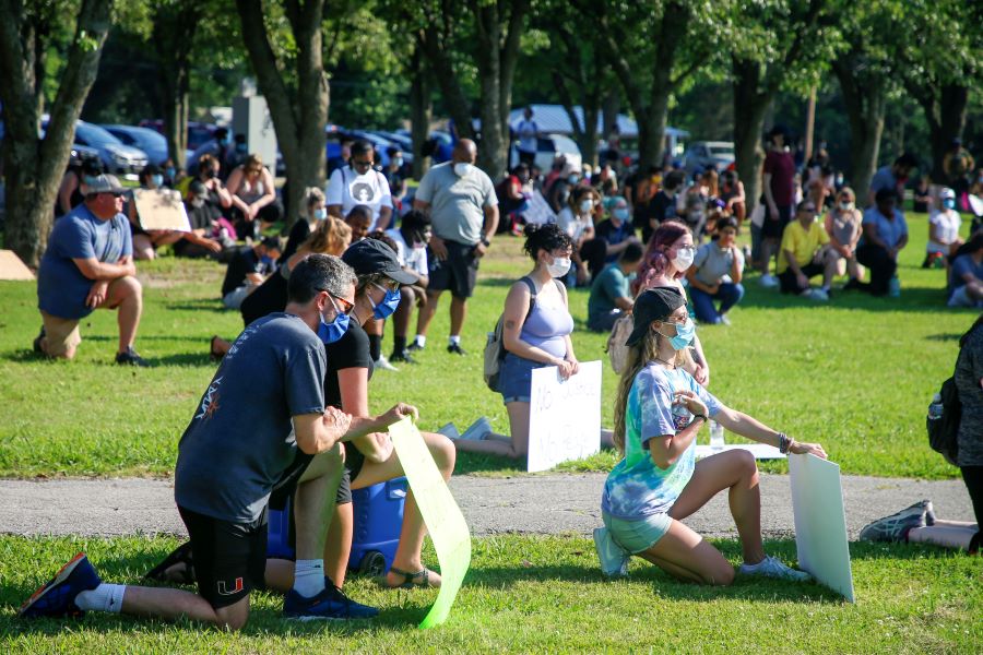 In this Saturday, June 6, 2020 photo, protesters kneel for 8 minutes and 46 seconds during a rally at Central Park, in Broken Arrow, Okla., in honor of George Floyd, a black man who died last month after being restrained by Minneapolis police. (Ian Maule/Tulsa World via AP