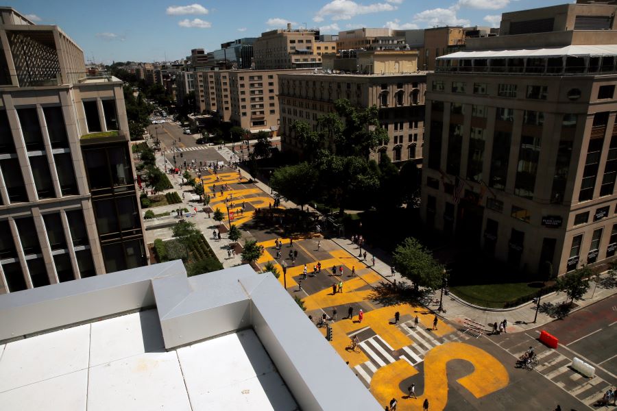 People walk on the words Black Lives Matter that was painted in bright yellow letters on 16th Street as demonstrators protest Sunday, June 7, 2020, near the White House in Washington, over the death of George Floyd, a black man who was in police custody in Minneapolis. Floyd died after being restrained by Minneapolis police officers on Memorial Day. (AP Photo/Maya Alleruzzo)