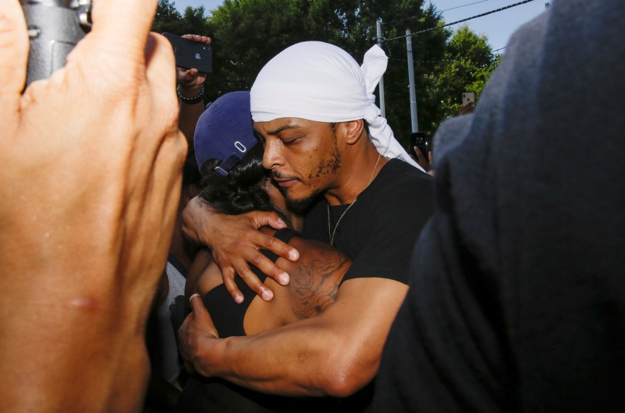 Rapper T.I. hugs a family member of Rayshard Brooks during protests, Saturday, June 13, 2020, near the Wendy's restaurant where Brooks was shot and killed by police Friday evening following a struggle in the restaurant's drive-thru line in Atlanta. (AP Photo/Brynn Anderson
