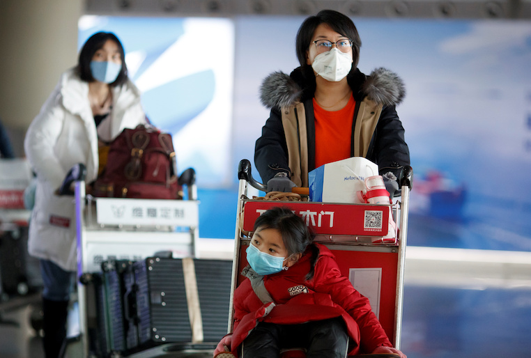 People wear face masks upon their arrival at Beijing Capital Airport, as the country is hit by an outbreak of the novel coronavirus, in Beijing, China, March 4, 2020. REUTERS/Thomas Peter