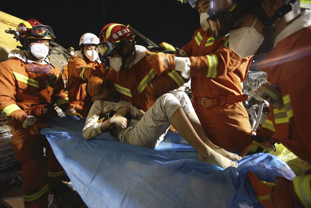 In this March 9, 2020 photo released by Xinhua News Agency, rescuers place a boy pulled from the rubbles of a collapsed hotel on a stretcher in Quanzhou, southeast China's Fujian Province. (Zeng Demeng/Xinhua via AP)