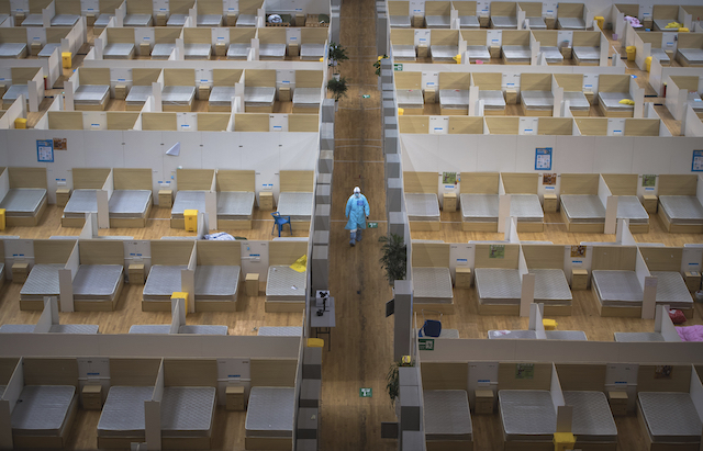 In this March 8, 2020, photo released by Xinhua News Agency, a staff member walks down a corridor of an empty makeshift hospital in Wuhan, central China's Hubei Province. The makeshift hospital converted from a sports venue was officially closed on Sunday after its last batch of cured COVID-19 patients were discharged. (Xiao Yijiu/Xinhua via AP)