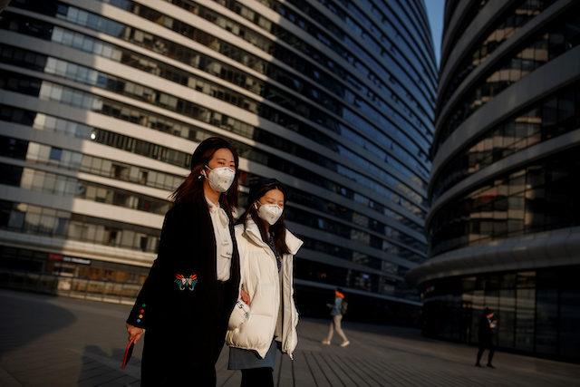 Women wears face masks outside an office complex in Beijing as the country is hit by an outbreak of the novel coronavirus, China, March 11, 2020. REUTERS/Thomas Peter