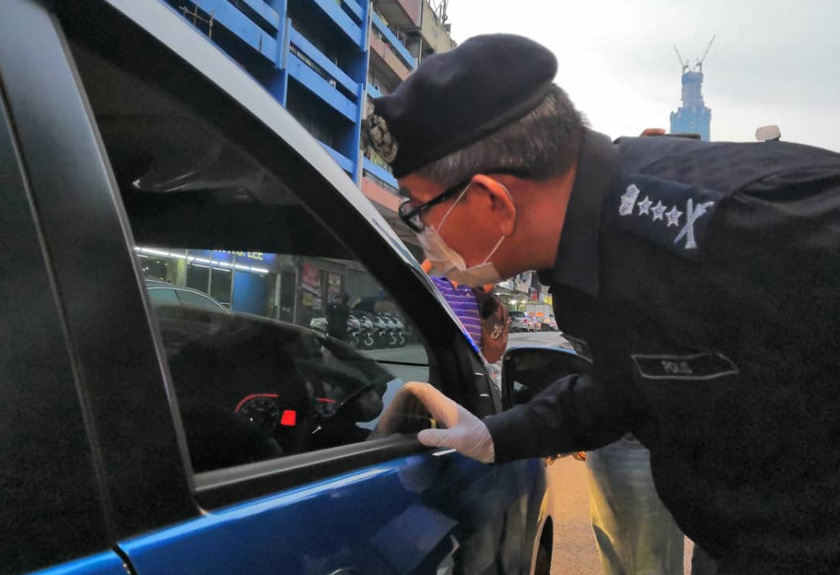 Mazlan (kanan) bertanyakan sesuatu kepada pemandu sebuah kereta dalam satu sekatan jalan raya di Jalan Loke Yew, di sini.