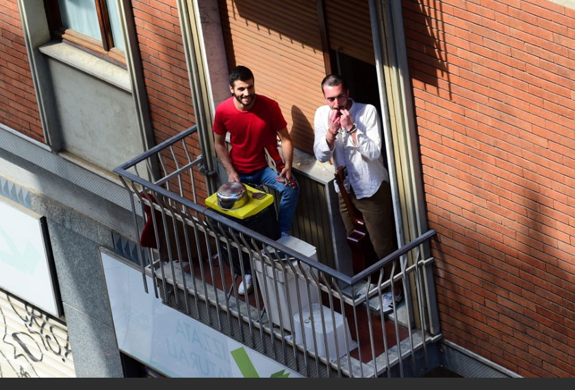 Penduduk tempatan berkongsi semangat dengan jiran-jiran dari ruang balkoni. - Reuters