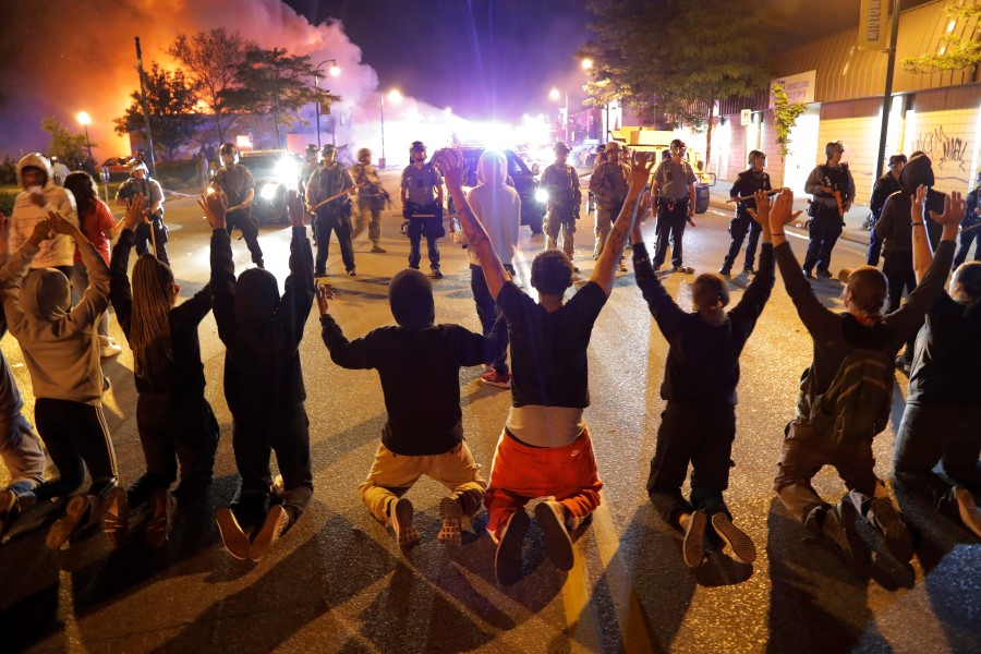Demonstrators kneel before police Saturday, May 30, 2020, in Minneapolis. Protests continued following the death of George Floyd, who died after being restrained by Minneapolis police officers on Memorial Day. (AP Photo/Julio Cortez)