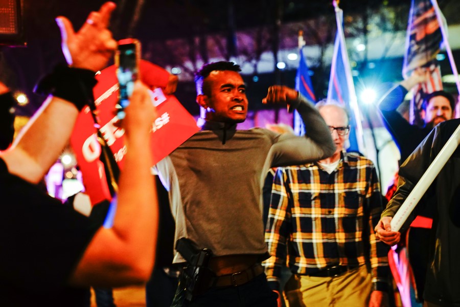 A Black supporter of U.S. President Donald Trump with a holstered pistol flexes as Trump supporters argue with Black Lives Matter counterprotesters at a 