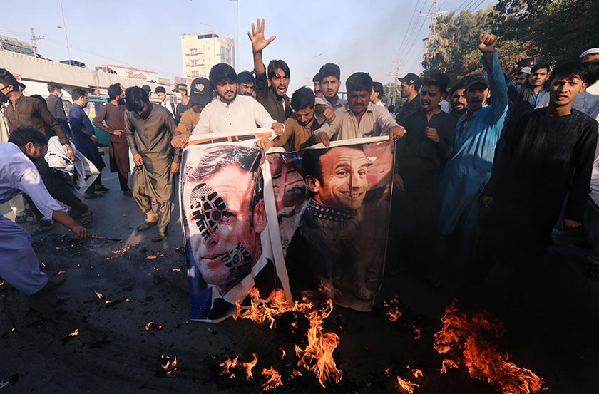 People chant slogans as they set fire to a banner with an image of French President Emmanuel Macron during a protest in Peshawar, Pakistan October 27, 2020. - REUTERS/Fayaz Aziz