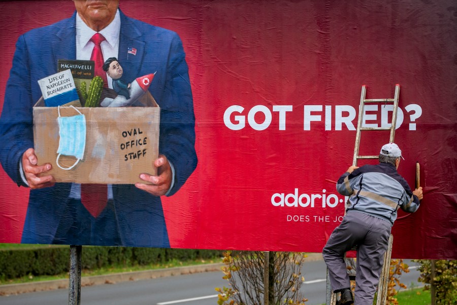 A worker puts up an advertising billboard for a recruiting company, featuring what resembles US President Donald Trump, in Zagreb, Croatia, Saturday, Nov. 7, 2020. (AP Photo/Darko Bandic)