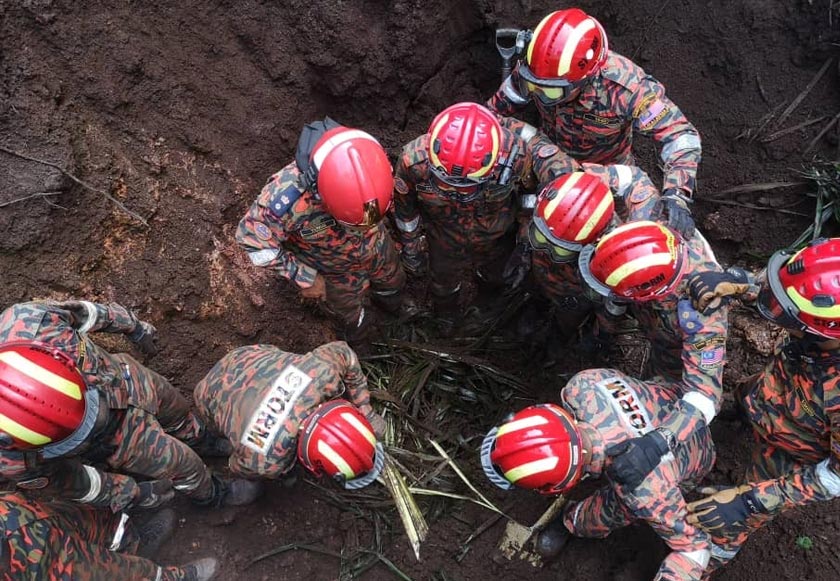 Anggota bomba menjalankan kerja-kerja mengeluarkan dua mangsa tertimbus. Foto JBPM