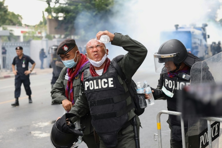 A policeman rinses tear gas from his eyes during the huge protest in Bangkok  - AFP