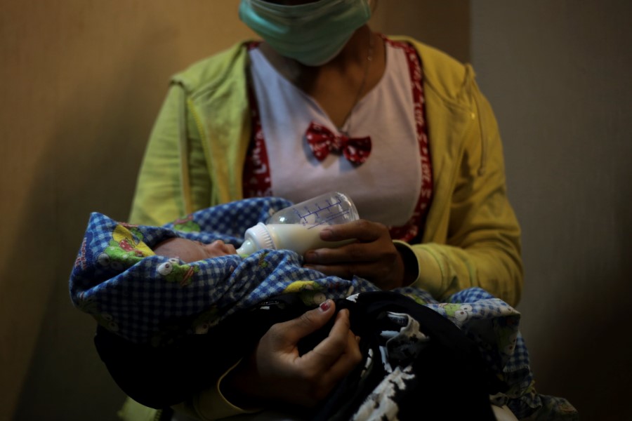 A 17-year-old mother gives a bottle to her 2-week-old baby, whom she says was born as a result of a rape in Sumatra, Indonesia, Sunday, Sept. 9, 2018. She started working on a plantation as a young child to help her family survive, never going to school or learning how to read or write. One day she said her boss took her alone to a quiet part of the estate. After the attack, while still half-naked, she said the man held a blade to her throat.