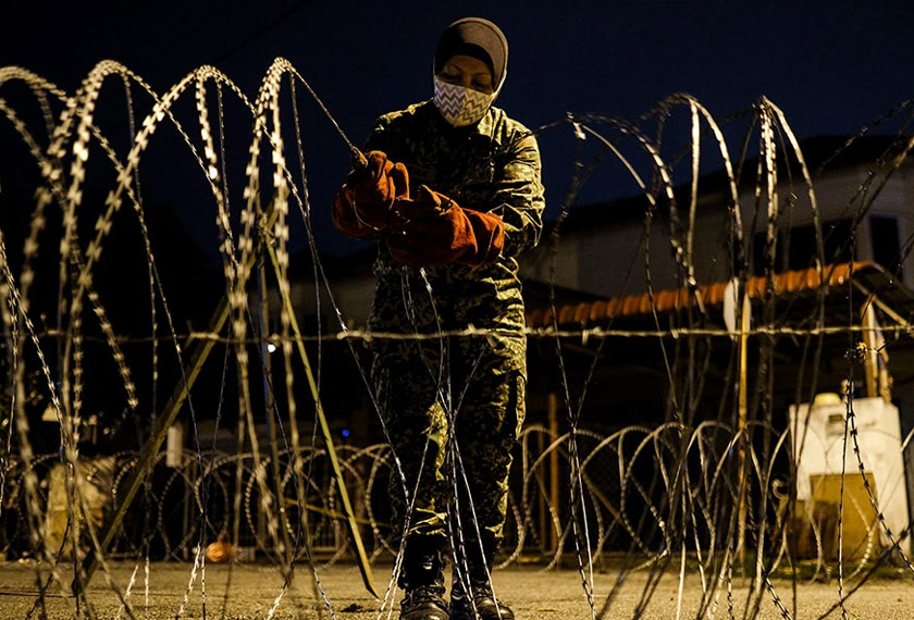 An army member put up a barbed wire in front of the Top Glove workers’ dormitories at Jalan Abadi 1A Meru. - Astro AWANI / Shahir Omar