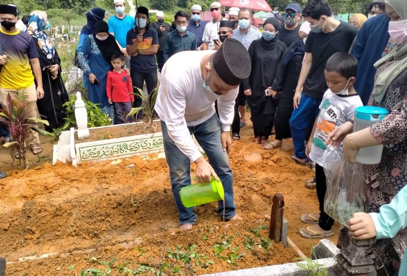 Faizul Hafiz Hashim menyiram air di kubur ibunya, Allahyarham Noryati Taib. – Gambar Astro AWANI