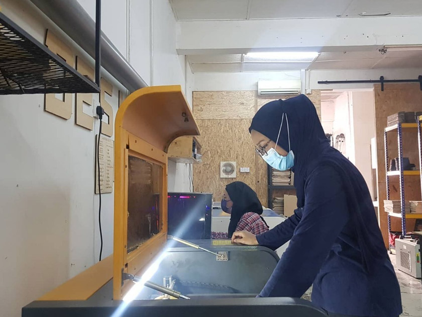 Pekerja Doktor Kayu sedang menyiapkan tempahan pelanggan menggunakan teknologi laser.