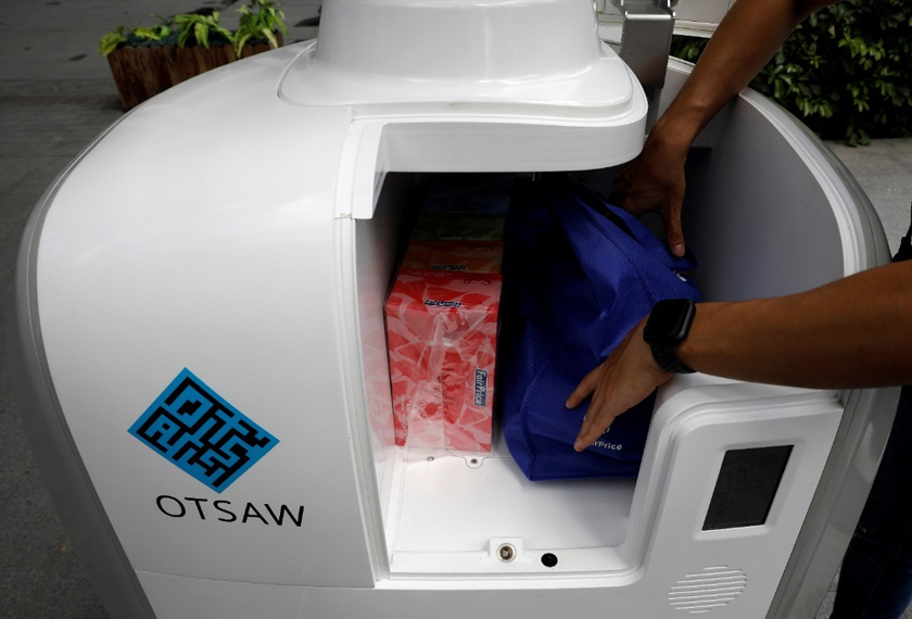 A staff member loads groceries into Camello, an autonomous grocery delivery robot, in Singapore. - REUTERS