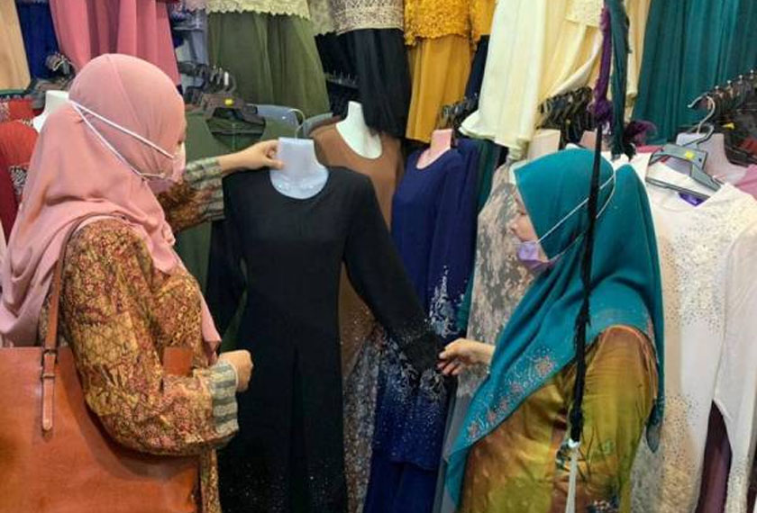 Azizah Omar (kanan) melayani pelanggan di kedainya untuk mencari pakaian. - Foto Sinar Harian