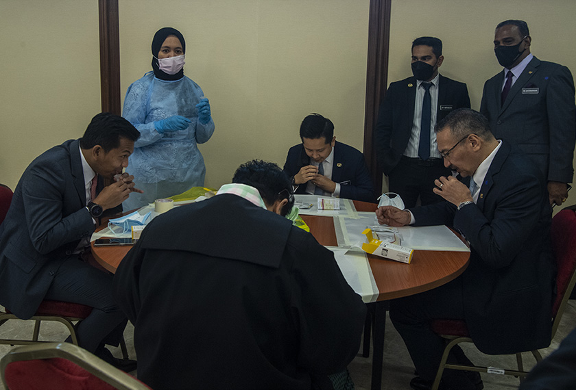 Menteri Kanan Luar Negeri Datuk Seri Hishammuddin Hussein (duduk, kanan) dan Timbalan Menteri Kewangan II Mohd Shahar Abdullah (duduk, kiri) melakukan ujian kendiri menggunakan kit Gmate Covid-19 Saliva Antigen apabila kakitangan dan ahli-ahli parlimen diarah melakukan ujian tersebut, 29 Julai, 2021. --fotoBERNAMA