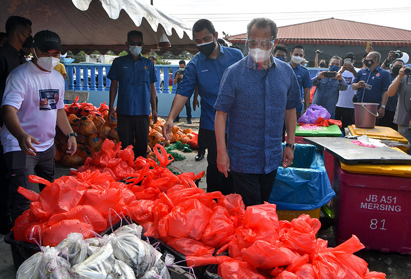 Muhyiddin Yassin (empat,kiri) melihat barangan sumbangan yang akan diagihkan kepada penduduk pada majlis Sumbangan Makanan Basah dan Bakul Prihatin kepada Penghulu-Penghulu di Kompleks Penghulu Mukim Sungai Raya, hari ini.