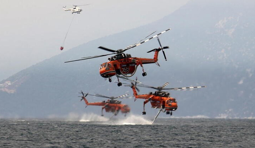 Firefighting helicopters are filled with water off the beach of the village of Pefki, on the island of Evia, Greece, August 10, 2021. REUTERS
