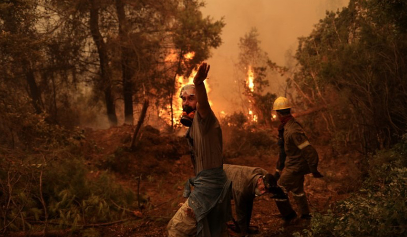 A volunteer reacts as a wildfire burns in the village of Galatsona, on the island of Evia, Greece. -REUTERS
